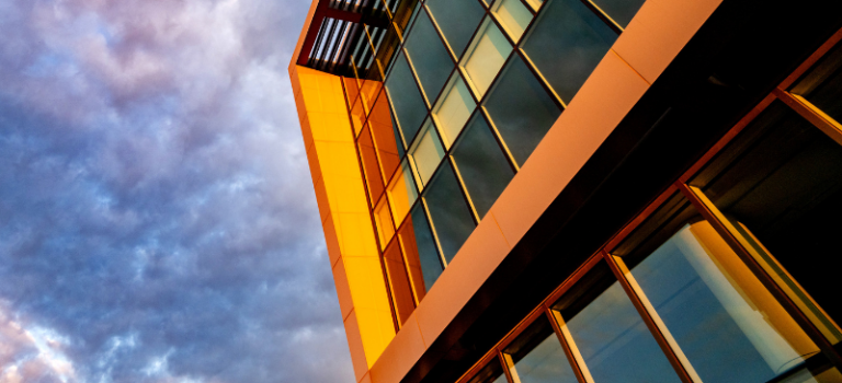 An close up of a building on the NCSU campus. Purple and blue clouds are in the background.