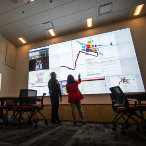 Two workers look at a giant projector.