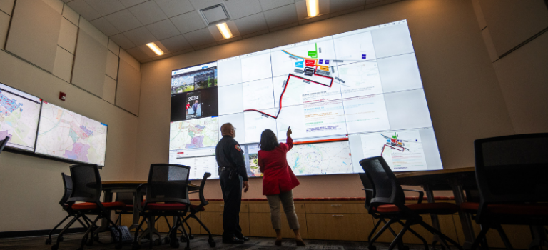 Two workers look at a giant projector.