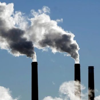 Pollution clouds streaming into a blue sky.