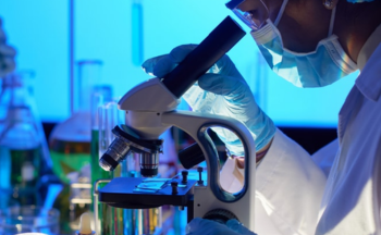 A scientist looking into a microscope.